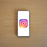 A smartphone with the Instagram logo on display, placed on a wooden surface. Perfect for technology and social media themes.